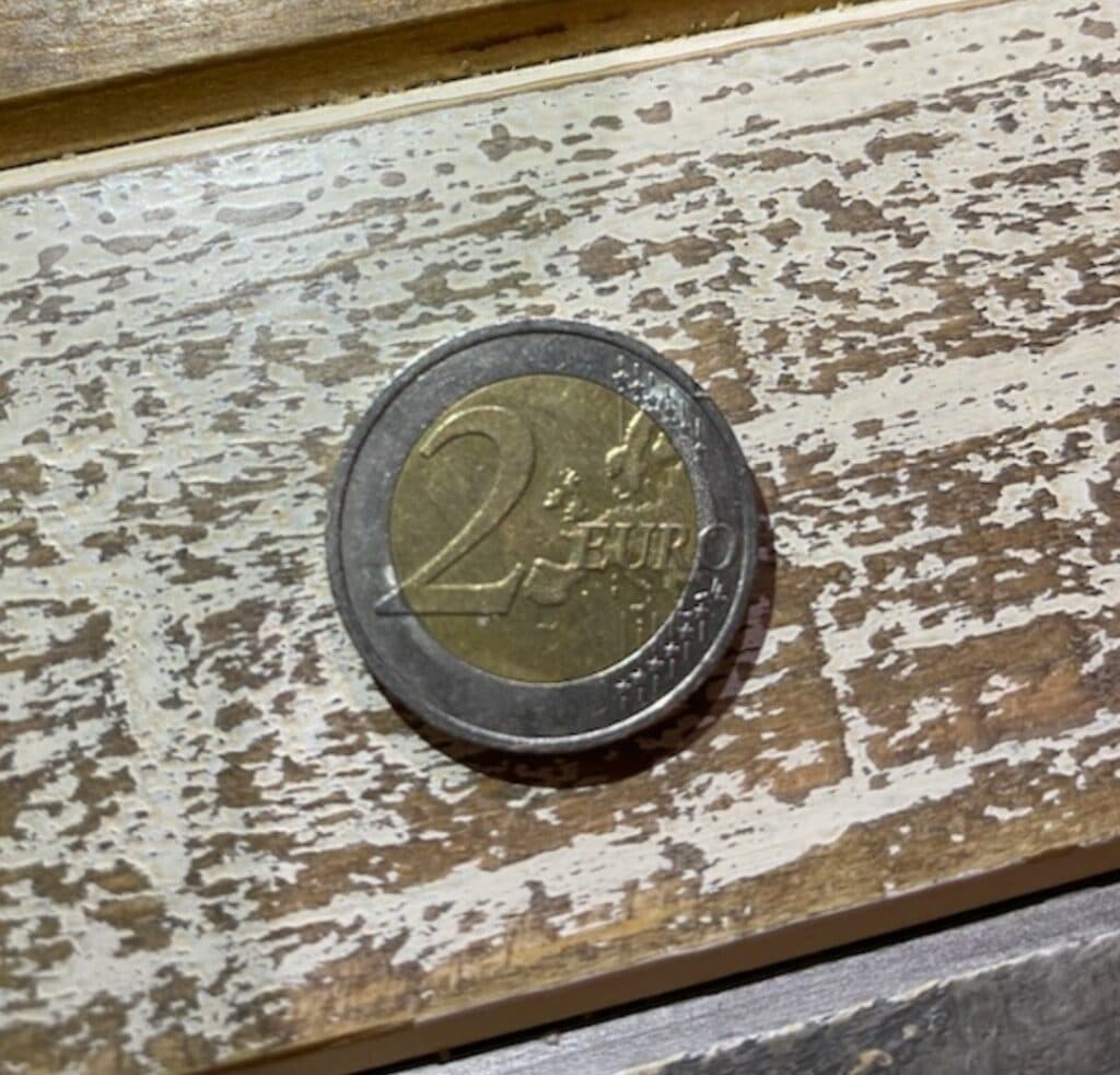 Taxatie van de monetaire waarde en medaille van de 2 EUR munt met een klein mannetje in reliëf. Taxatie van de monetaire waarde en medaille van de 2 EUR munt met een klein mannetje in reliëf.