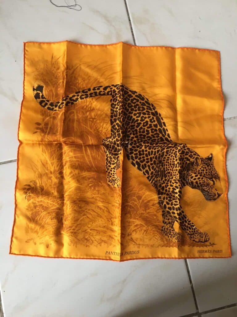 Taxatie van een vintage Hermès zijden sjaal met een pantermotief in de savanne, in oranje kleur, met afmetingen van 40×40 cm, voor handtas. Taxatie van een vintage Hermès zijden sjaal met een pantermotief in de savanne, in oranje kleur, met afmetingen van 40×40 cm, voor handtas.