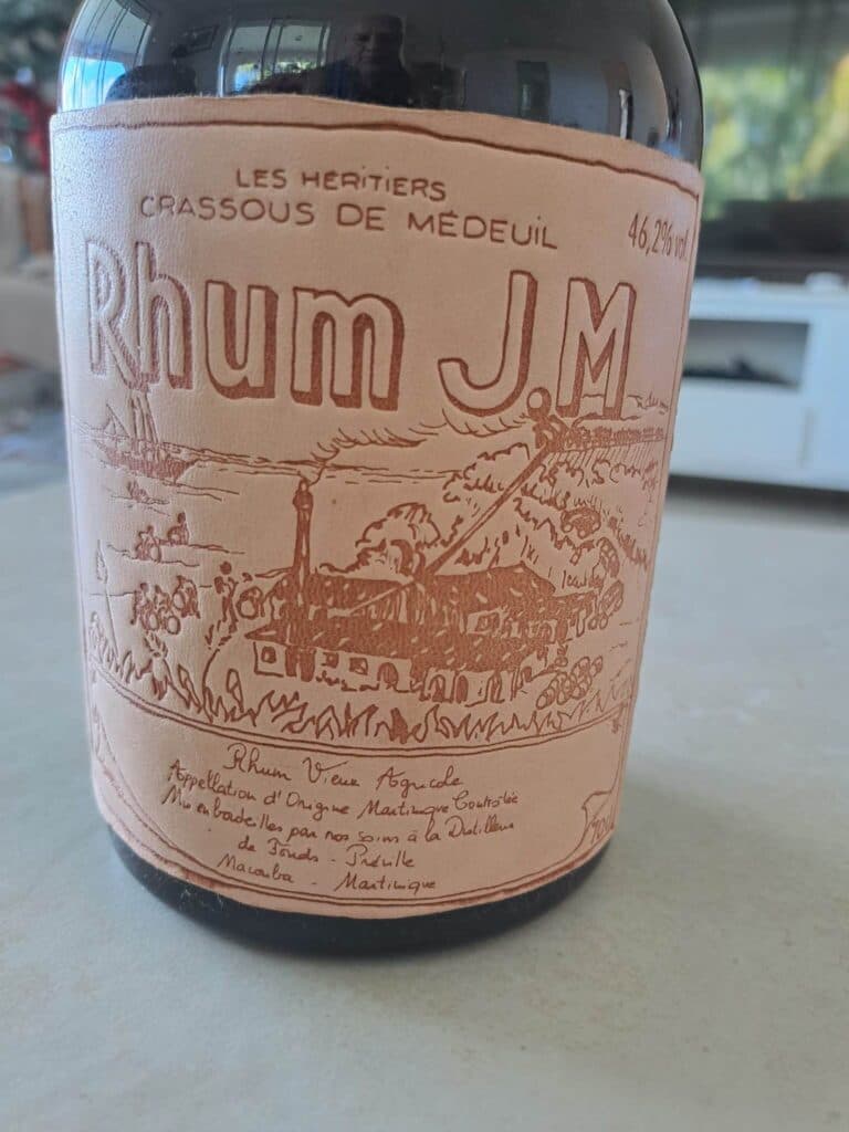 Taxatie van een fles oude Rhum JM Crassous de Medeuil uit 1988, gepresenteerd in een houten kist met inhoud, intacte kurk en etiketten.