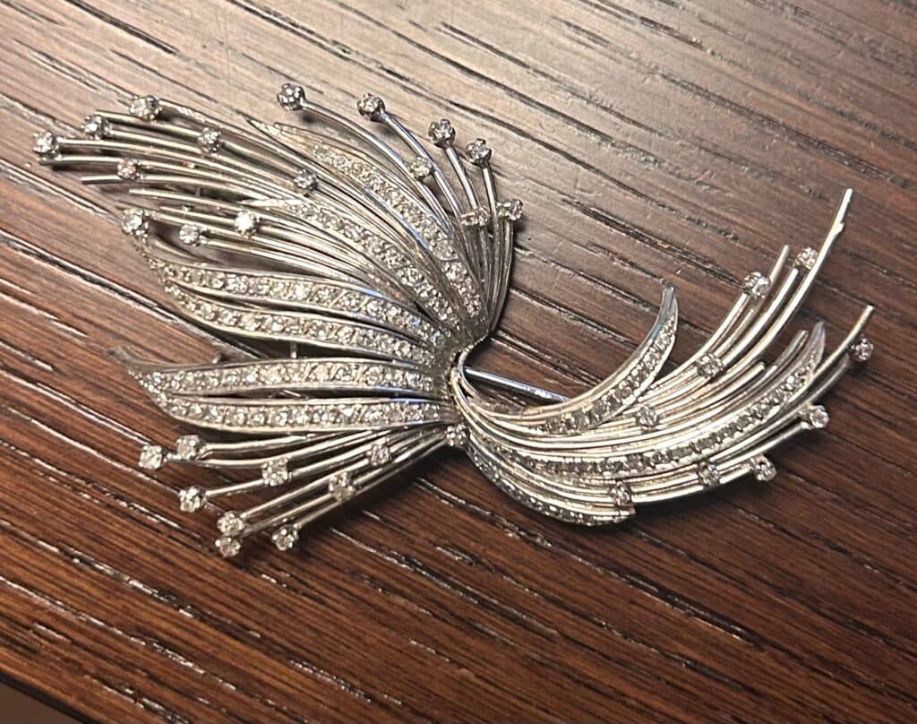 Taxatie van de waarde van een broche in witgoud of platina in Art Nouveau-stijl zonder zichtbaar keurmerk, met een gewicht van 23g. Taxatie van de waarde van een broche in witgoud of platina in Art Nouveau-stijl zonder zichtbaar keurmerk, met een gewicht van 23g.